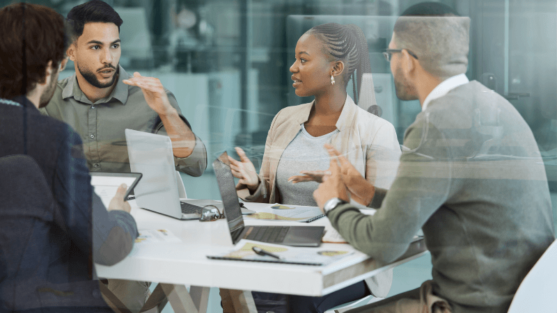 Senior Compliance Professionals Discussing Financial Services Regulation And Risk In A US Office Meeting.